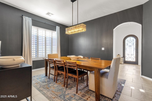 dining space featuring visible vents, arched walkways, baseboards, and light tile patterned floors