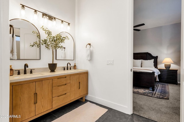 ensuite bathroom featuring double vanity, baseboards, a sink, and tile patterned flooring