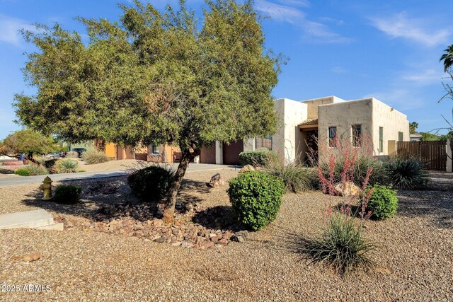 view of front of home with an attached garage, stucco siding, and fence
