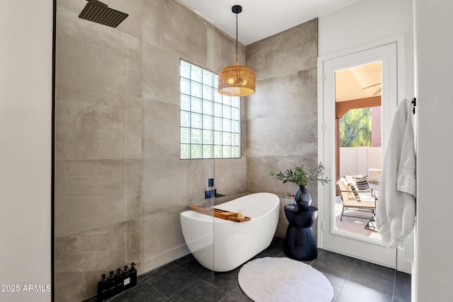 bathroom featuring tile patterned floors, tile walls, a healthy amount of sunlight, and a freestanding tub