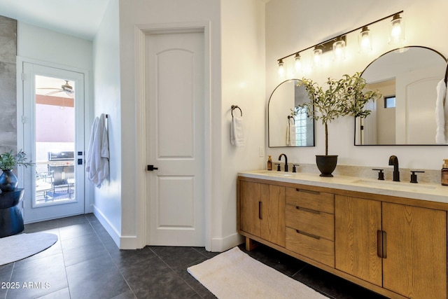 full bathroom featuring double vanity, baseboards, a sink, and tile patterned flooring