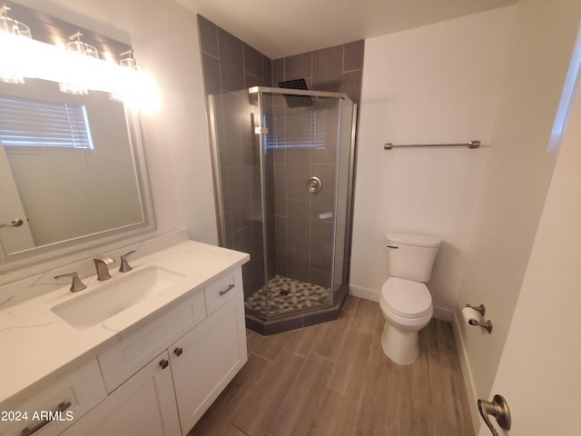 bathroom with hardwood / wood-style floors, vanity, toilet, and an enclosed shower