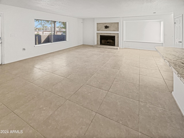 unfurnished living room featuring a textured ceiling and light tile patterned flooring