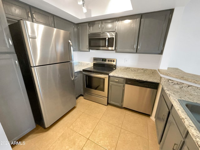 kitchen featuring gray cabinets, light stone counters, stainless steel appliances, and light tile patterned flooring