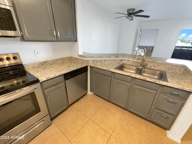 kitchen with gray cabinetry, light tile patterned floors, appliances with stainless steel finishes, sink, and ceiling fan