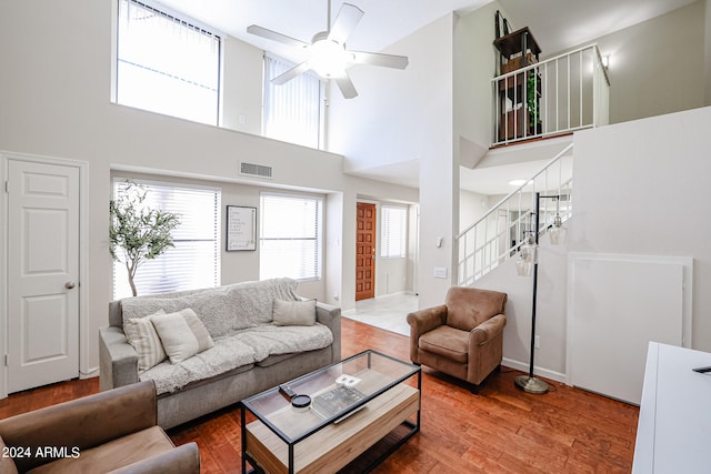 living room featuring a towering ceiling, hardwood / wood-style floors, and ceiling fan