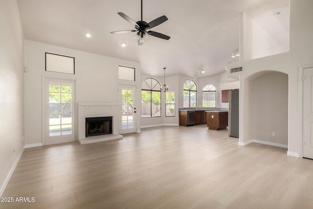 319 N Riata St, Gilbert, AZ 85234 - unfurnished living room featuring healthy amount of natural light, a fireplace with raised hearth, vaulted ceiling, ceiling fan, and light wood-style floors