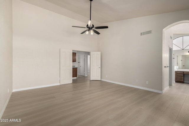 319 N Riata St, Gilbert, AZ 85234 - unfurnished living room featuring arched walkways, ceiling fan, light wood finished floors, and high vaulted ceiling
