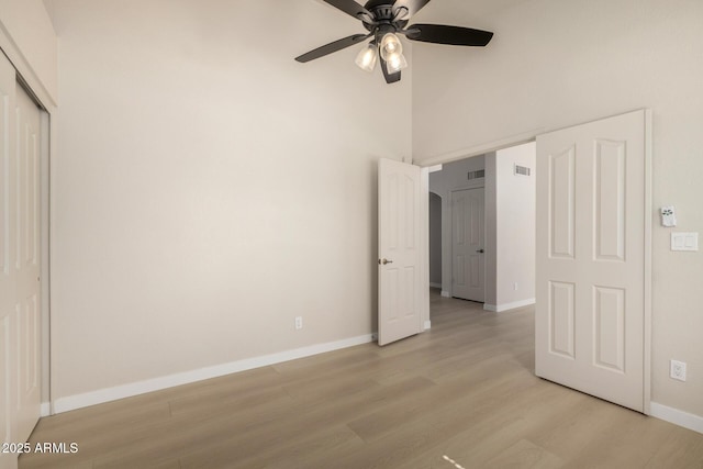 319 N Riata St, Gilbert, AZ 85234 - unfurnished bedroom with light wood-style floors, a closet, a towering ceiling, and a ceiling fan