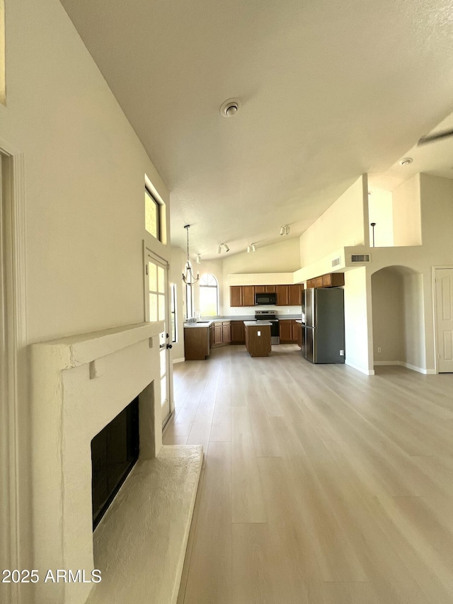 319 N Riata St, Gilbert, AZ 85234 - unfurnished living room with a fireplace with raised hearth, arched walkways, light wood-type flooring, and high vaulted ceiling