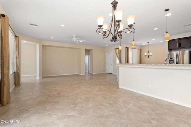 kitchen with light stone counters, dark brown cabinets, ceiling fan with notable chandelier, stainless steel fridge with ice dispenser, and hanging light fixtures