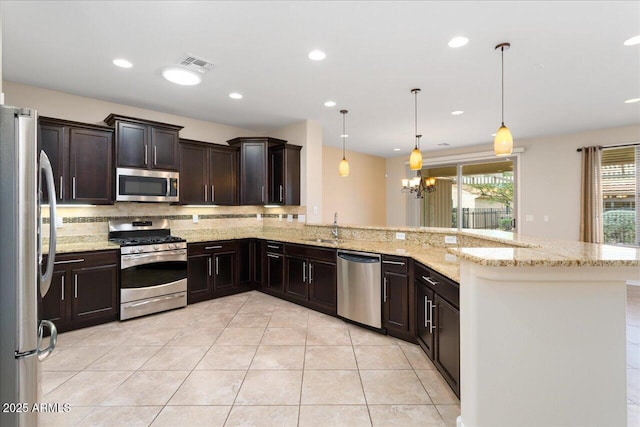 kitchen with sink, an inviting chandelier, kitchen peninsula, pendant lighting, and appliances with stainless steel finishes