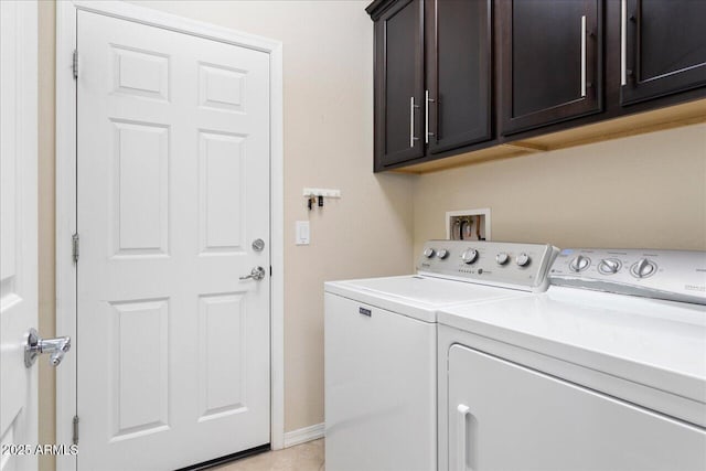 clothes washing area with cabinets and washing machine and clothes dryer