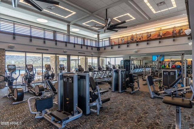 exercise room featuring ceiling fan, carpet floors, and a high ceiling