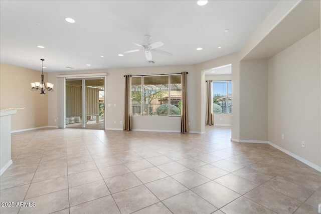 tiled spare room featuring ceiling fan with notable chandelier