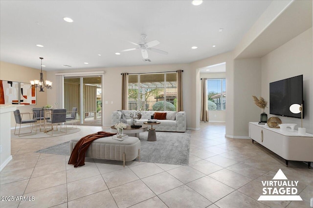 tiled living room featuring ceiling fan with notable chandelier