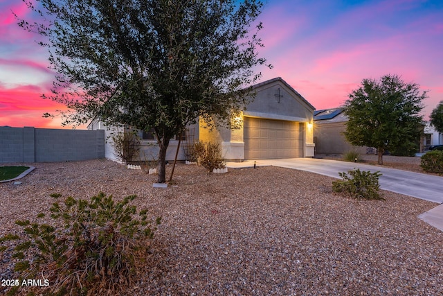 view of front facade featuring stucco siding, driveway, an attached garage, and fence