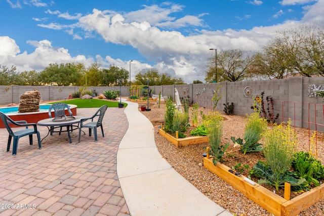 view of patio / terrace with a garden, a fenced in pool, and a fenced backyard