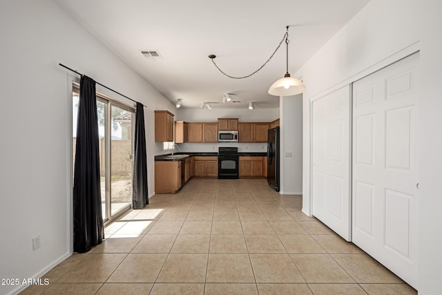 kitchen featuring light tile patterned floors, sink, pendant lighting, black fridge, and electric stove