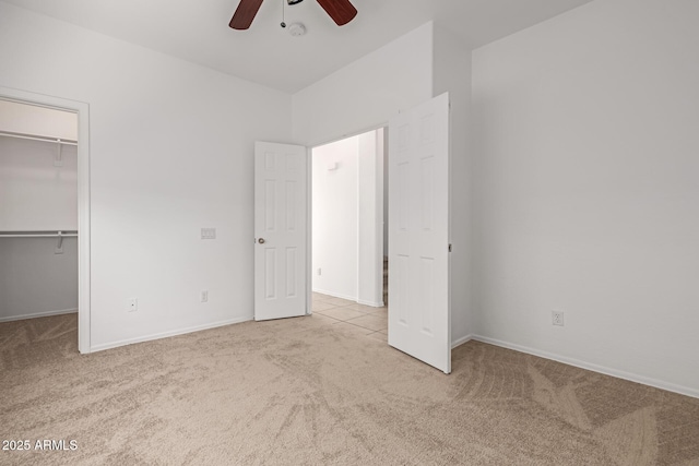 unfurnished bedroom with ceiling fan, light carpet, a closet, and a spacious closet