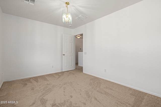 carpeted spare room with an inviting chandelier