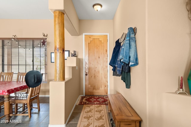 doorway to outside with decorative columns and dark tile patterned flooring