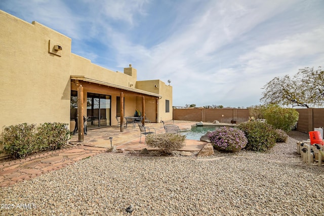 rear view of property with a patio and a fenced in pool