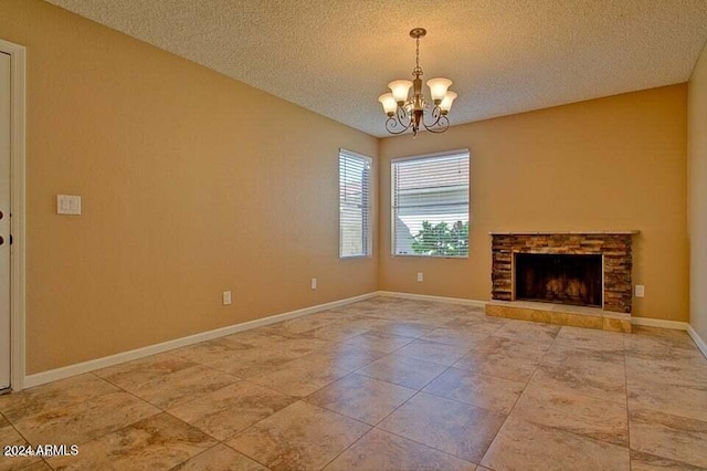 unfurnished living room featuring a fireplace, a textured ceiling, and a notable chandelier