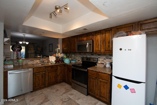 kitchen featuring a tray ceiling, tasteful backsplash, sink, and appliances with stainless steel finishes