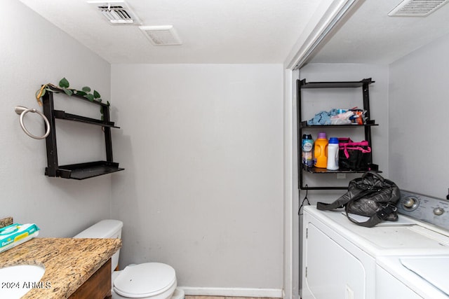 bathroom featuring washing machine and clothes dryer, vanity, and toilet