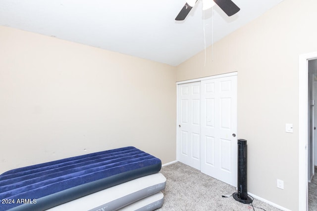 carpeted bedroom with ceiling fan, a closet, and vaulted ceiling