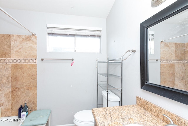 bathroom featuring vanity, toilet, and tiled shower