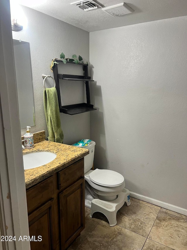 bathroom featuring a textured ceiling, vanity, and toilet