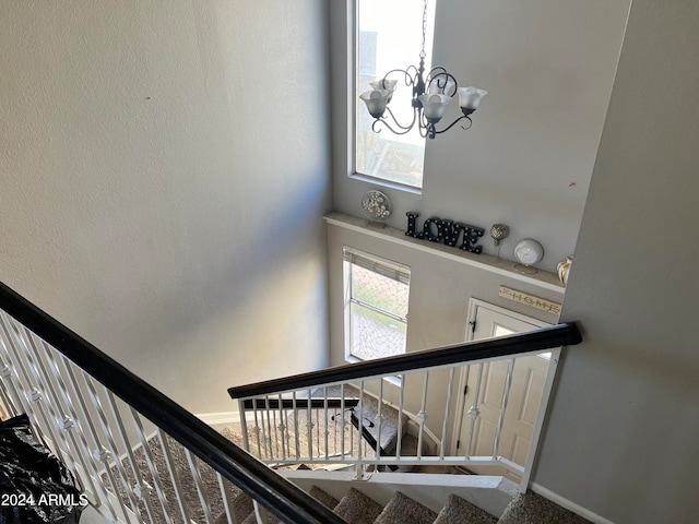 stairway with a notable chandelier