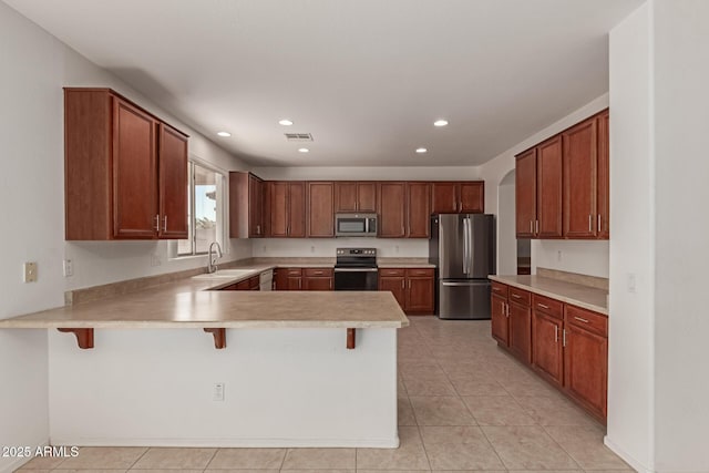 kitchen featuring appliances with stainless steel finishes, sink, a kitchen breakfast bar, light tile patterned floors, and kitchen peninsula