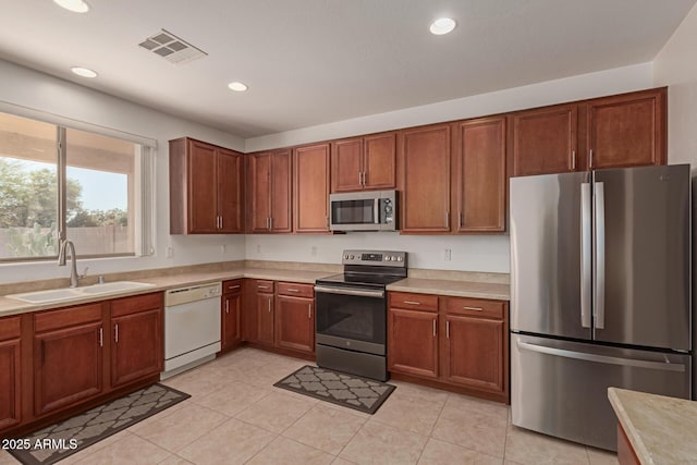 kitchen with appliances with stainless steel finishes, sink, and light tile patterned floors