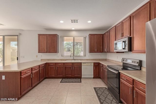 kitchen with sink, light tile patterned floors, stainless steel appliances, and kitchen peninsula