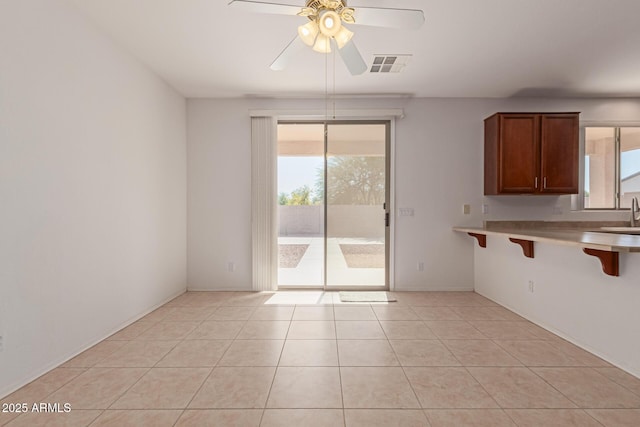 interior space featuring a breakfast bar area, light tile patterned floors, and ceiling fan