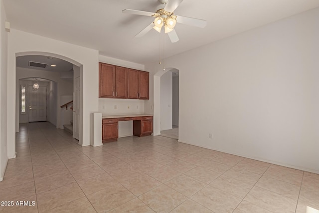 unfurnished room featuring light tile patterned floors, built in desk, and ceiling fan