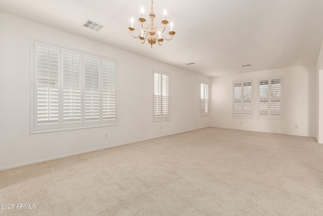 spare room featuring light carpet and a notable chandelier