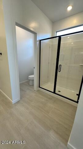 bathroom featuring hardwood / wood-style floors, toilet, and an enclosed shower