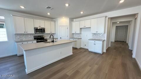 kitchen featuring white cabinets, sink, black range oven, and a center island with sink