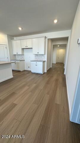 kitchen with dark hardwood / wood-style flooring, white cabinetry, and backsplash