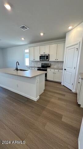 kitchen with dark hardwood / wood-style flooring, sink, white cabinets, and a center island with sink