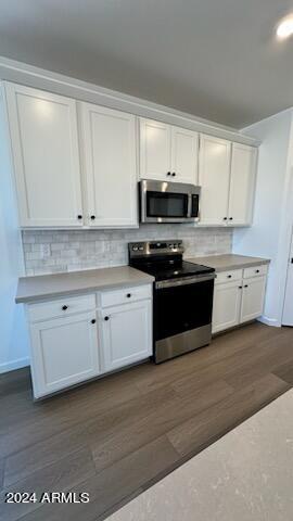 kitchen featuring backsplash, white cabinetry, stainless steel appliances, and dark hardwood / wood-style floors