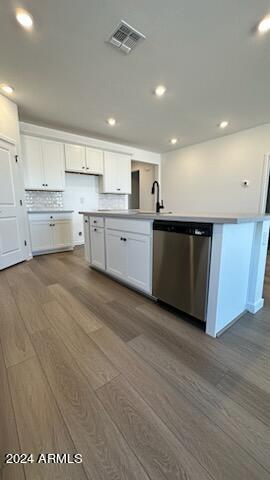 kitchen with stainless steel dishwasher, light wood-type flooring, and white cabinetry