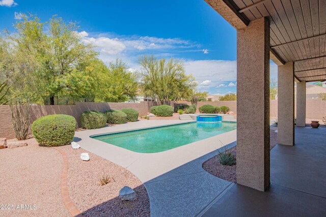 view of swimming pool featuring a patio, a pool with connected hot tub, and a fenced backyard