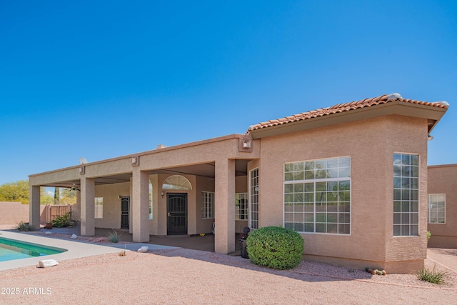 back of property with fence, a patio, stucco siding, and a tile roof