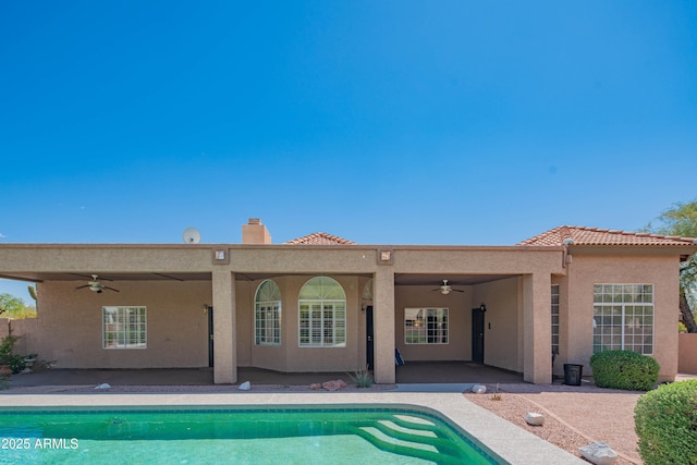 rear view of property with ceiling fan, a patio, stucco siding, a chimney, and a tiled roof