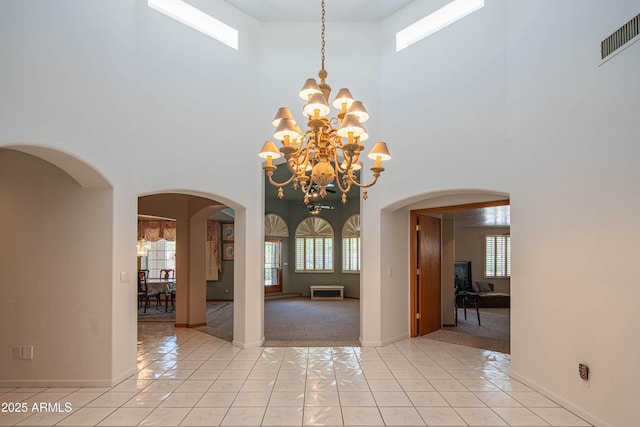 interior space featuring visible vents, a high ceiling, a wealth of natural light, and an inviting chandelier